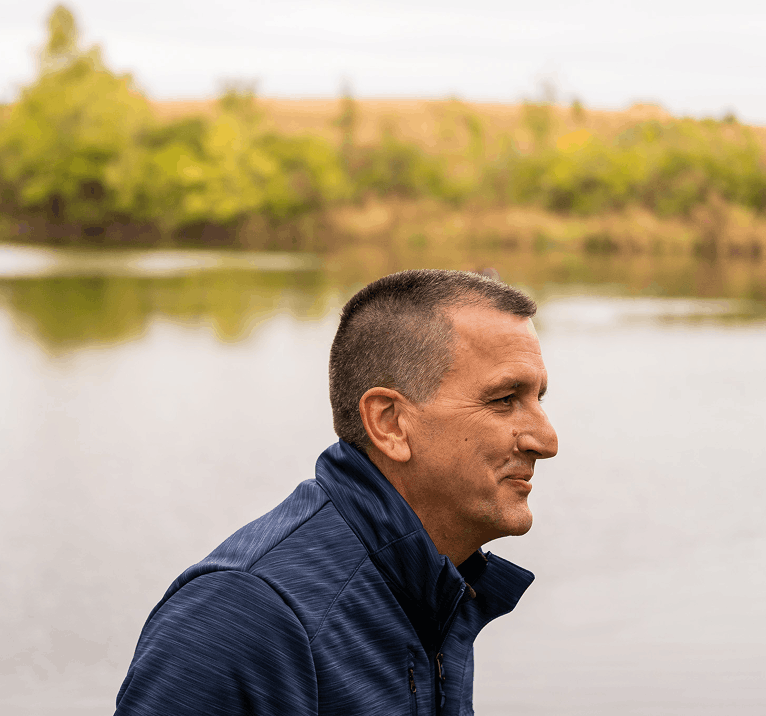 Team member standing by a lake