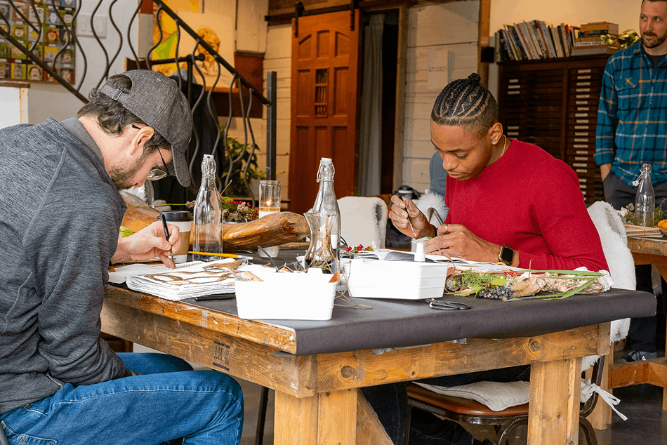 Two team members painting at a wooden table